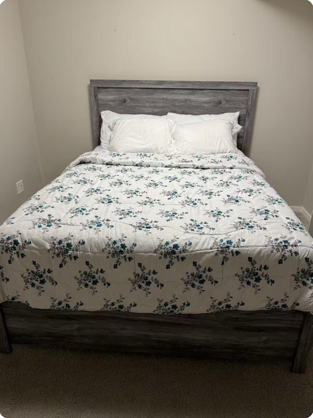 Ein Bett mit einer blumigen Bettdecke und einem Holzkopfende.
