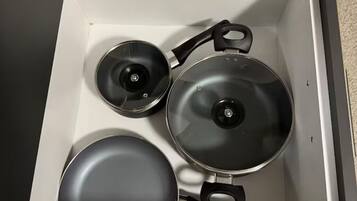 A kitchen drawer with three pots and pans.