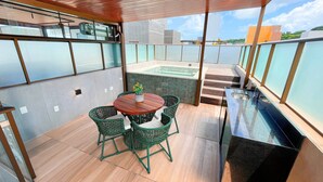 A balcony with a wooden table, green wicker chairs, a glass-top sink, and a hot tub. - FM20 Cabo Branco Premium I - By Almare (Joao Pessoa)