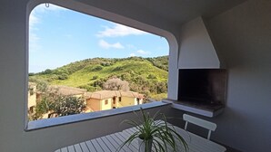 Ein Balkon mit Blick auf eine Hügellandschaft und traditionelle Gebäude.