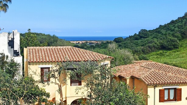Ein Küstengebäude mit Ziegeldach, umgeben von Grün und mit Blick auf das Meer.