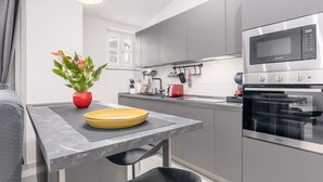 A modern kitchen with grey cabinets, a stainless steel oven, and a red toaster.