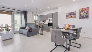 A modern apartment with a dining area, kitchen, and a balcony with a view.