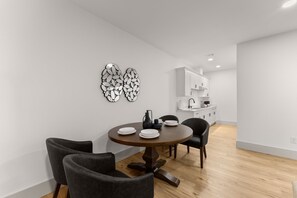 Un espace repas moderne avec une table ronde en bois, deux chaises et des œuvres d’art décoratives accrochées au mur.