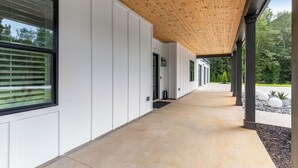 Un bâtiment moderne doté d’une galerie couverte, de grandes fenêtres et offrant une vue sur la verdure.