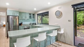 Una cocina moderna con una isla central, electrodomésticos de acero inoxidable y vistas al exterior.