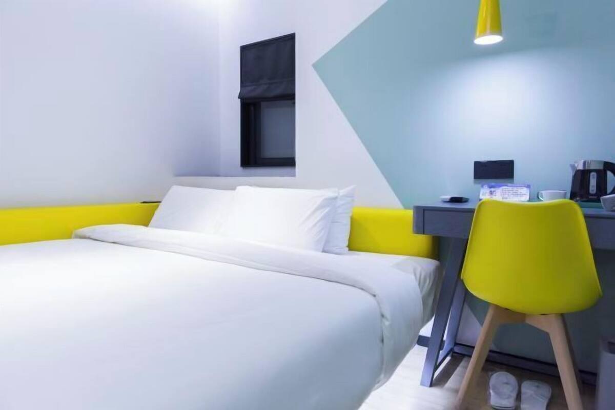 A hotel room with a bed, a desk, a chair, and a window.