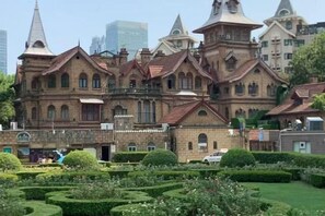 A large, historic building with multiple towers and a well-maintained garden in front. - Dingyi Hotel (Shanghai Ninth People's Hospital Lujia Bang Subway Station) (Shanghai)