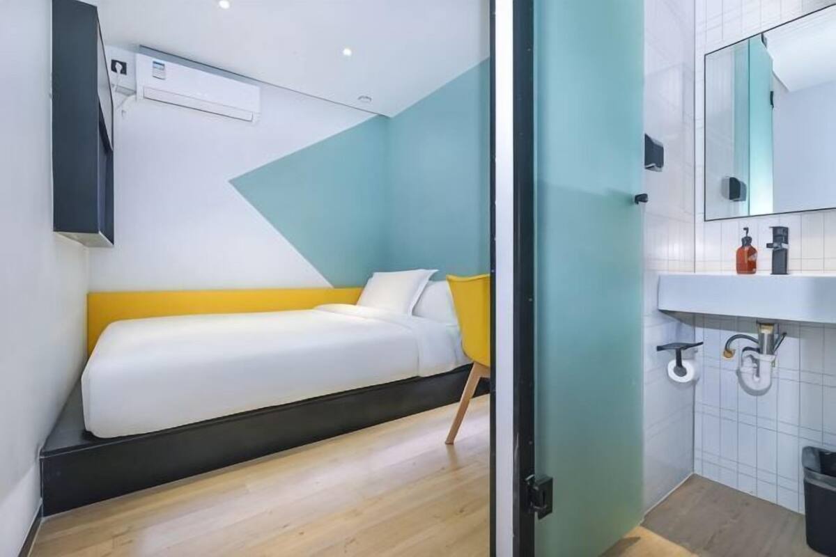 A room with a bed, a sink, and a mirror.
