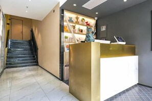 Zona de recepción con mostrador, escalera y pared decorada.