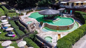 Un área de piscina con un pabellón, sillas de descanso y una cascada pequeña.