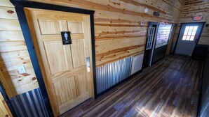 A wooden interior with a men’s restroom, a door marked "EXIT," and a vented wall. - RV Site 8 Camper - Hatfield McCoy Trails (Wilkinson)