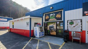 A building with a blue and white exterior, a sign for Hillbilly Rentals, and a parking lot with marked spaces. - RV Site 8 Camper - Hatfield McCoy Trails (Wilkinson)