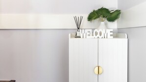 Una entrada moderna con una consola blanca que tiene un cartel que dice 'WELCOME', una planta pequeña y una lámpara fijada a la pared.