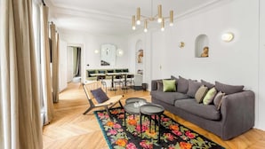 A modern living room with a grey sofa, a wooden floor, and a floral rug. - A PERFECT PARISIAN GETAWAY IN A PERFECT LOCATION – RUE DU TEMPLE (Paris)