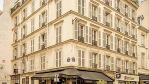 A multi-story building with a classic architectural style, featuring a corner entrance with a cafe and outdoor seating. - A PERFECT PARISIAN GETAWAY IN A PERFECT LOCATION – RUE DU TEMPLE (Paris)