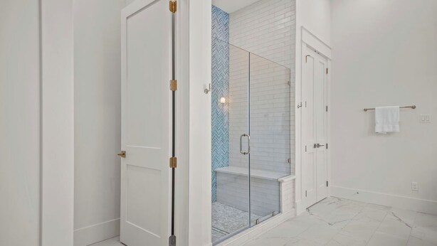 A modern bathroom with a glass-enclosed shower, white tiled walls, and a marble floor. - The Sandy Pearl 125 STA (Port Aransas)