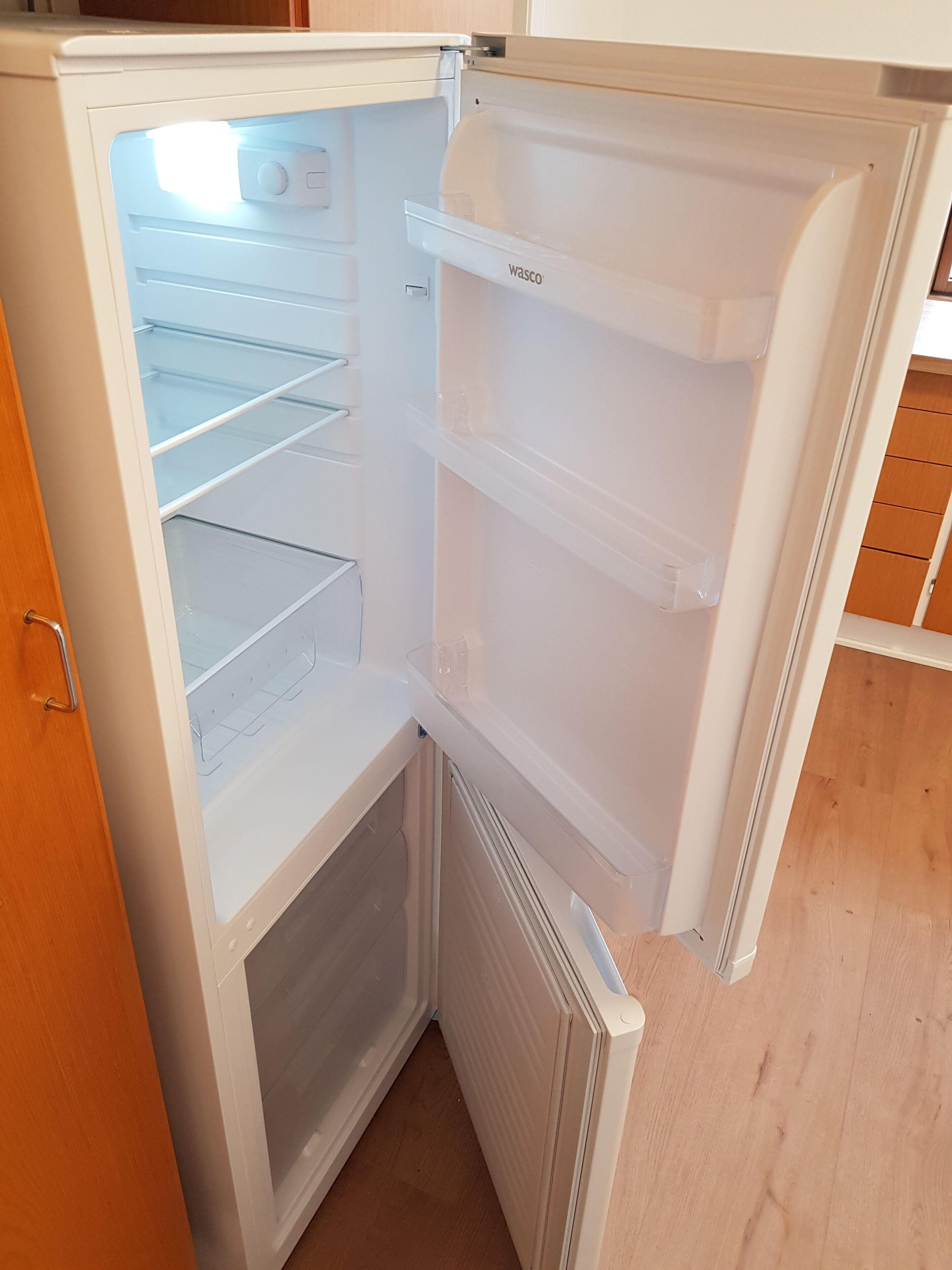 Ett kylskåp med öppna hyllor och ett separat frysfack.