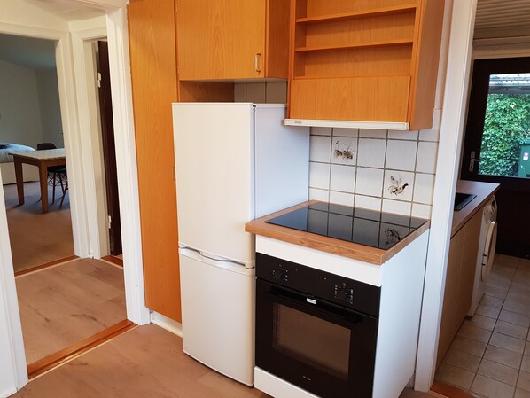 A compact kitchen with a refrigerator, oven, and wooden countertop. - Billund Retreat - 5 bedroom House (Billund)