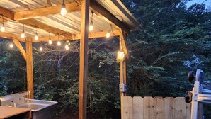 A wooden outdoor structure with a sink and bench, surrounded by trees. - Milky Way with AC and WiFi, glamping near Houston (Cleveland)
