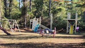 A playground with various play equipment including slides and swings, surrounded by trees. - Milky Way with AC and WiFi, glamping near Houston (Cleveland)