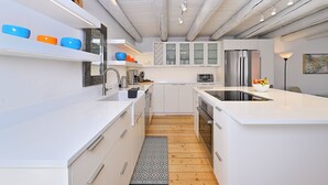 A modern kitchen with white cabinetry, a stainless steel refrigerator, and a wooden floor.