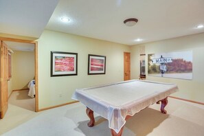A room with a pool table, two framed pictures on the wall, and a sign reading 'MAIN ST.'