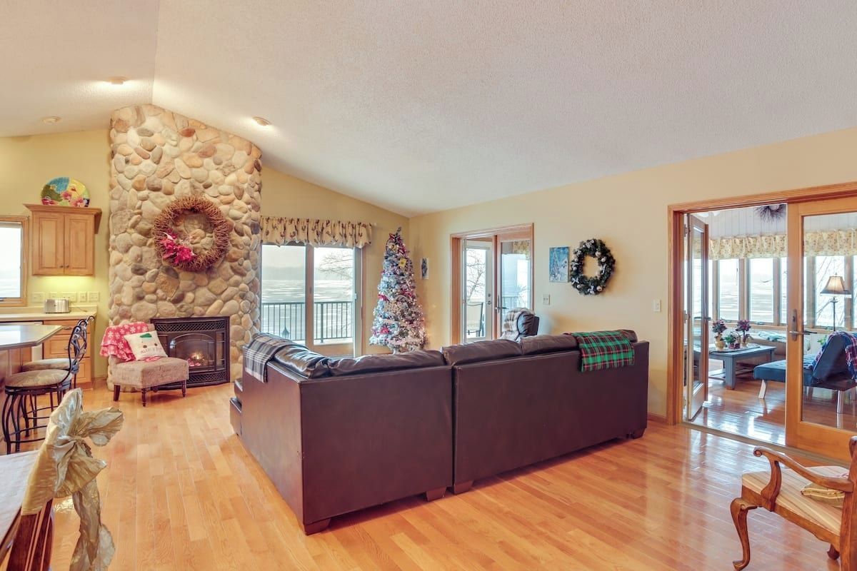 A spacious living room with a stone fireplace, a large sectional sofa, and a Christmas tree.