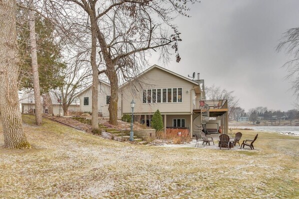 A two-story house with a covered porch, a small deck, and a view of a body of water.