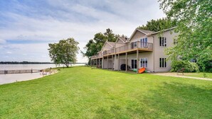 A two-story house with a balcony, a covered porch, and a view of a lake.