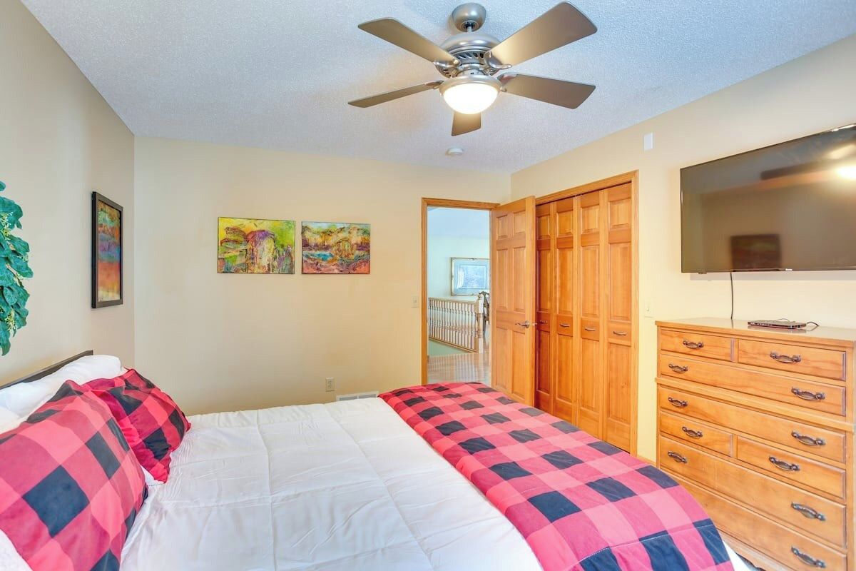 A bedroom with a bed, a ceiling fan, a dresser, and a television.