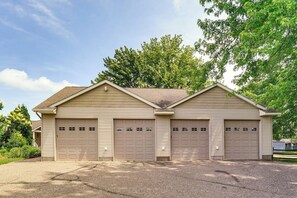 A two-story building with three garage doors, a sloped roof, and a gravel driveway.