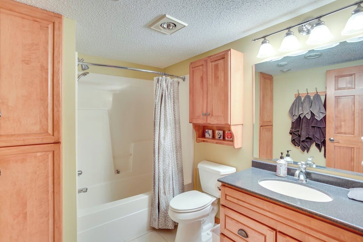 A bathroom with a bathtub, toilet, and vanity with a mirror.
