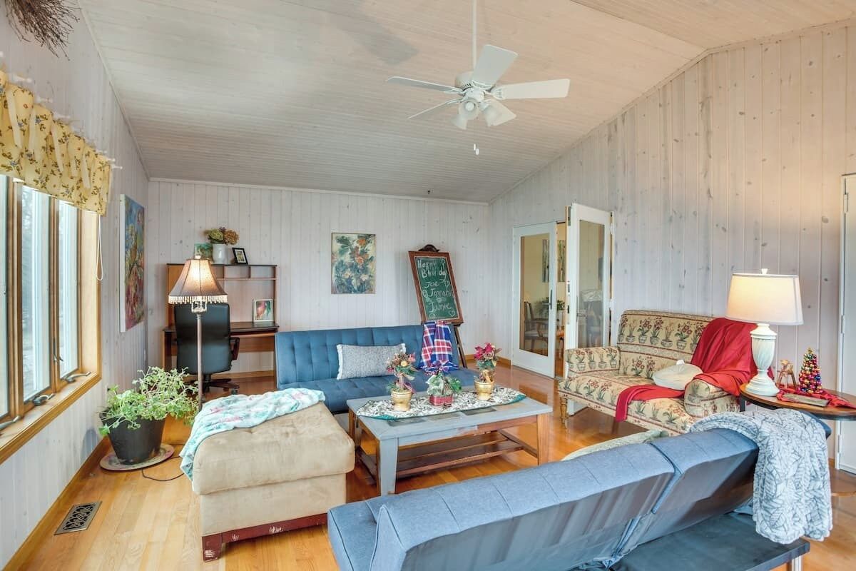 A cozy living room with a blue sofa, a wooden coffee table, and a ceiling fan.