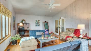 A cozy living room with a blue sofa, a wooden coffee table, and a ceiling fan.