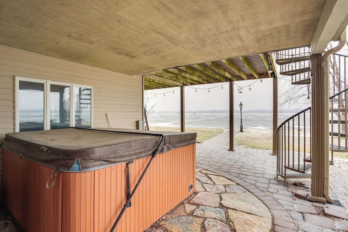 A hot tub under a pergola with a stone pathway leading to a staircase.