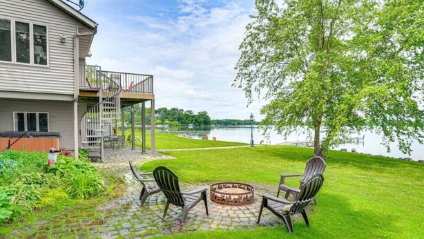 Une maison dotée d’un patio comprenant un foyer extérieur et des sièges.