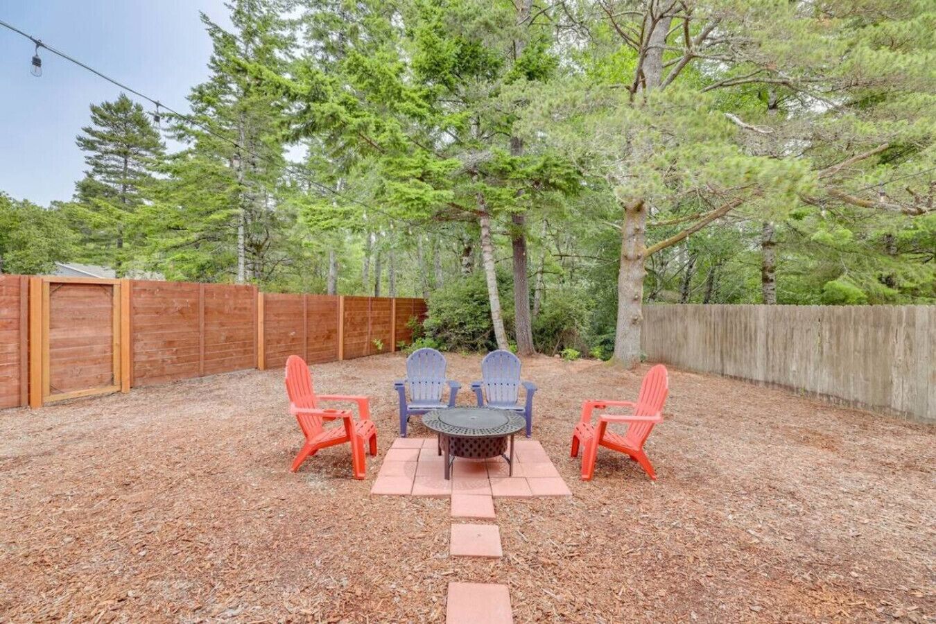 A backyard with a wooden fence, a table with chairs, and a wooden deck.