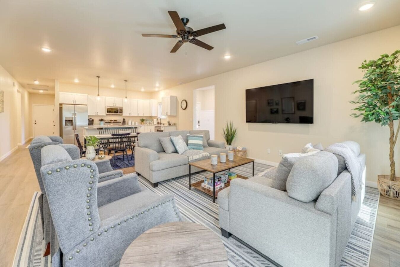 A modern living room with grey upholstered sofas, a coffee table, and a ceiling fan.