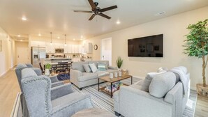 Ein modernes Wohnzimmer mit grauen gepolsterten Sofas, einem Couchtisch und einem Deckenventilator.