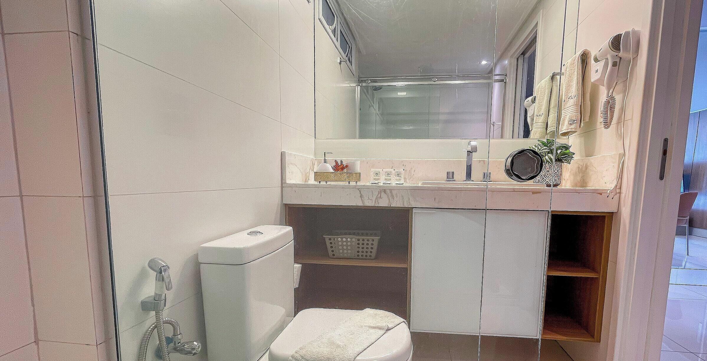 A compact bathroom with a toilet, a shower, and a sink.