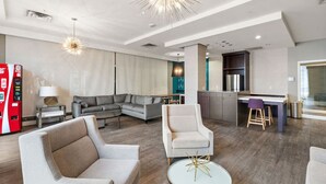 Een moderne hotelkamer met een zithoek, een eethoek en een kitchenette.