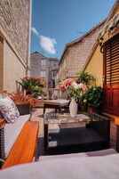 A cozy outdoor seating area with wicker furniture, a glass table, and potted plants.