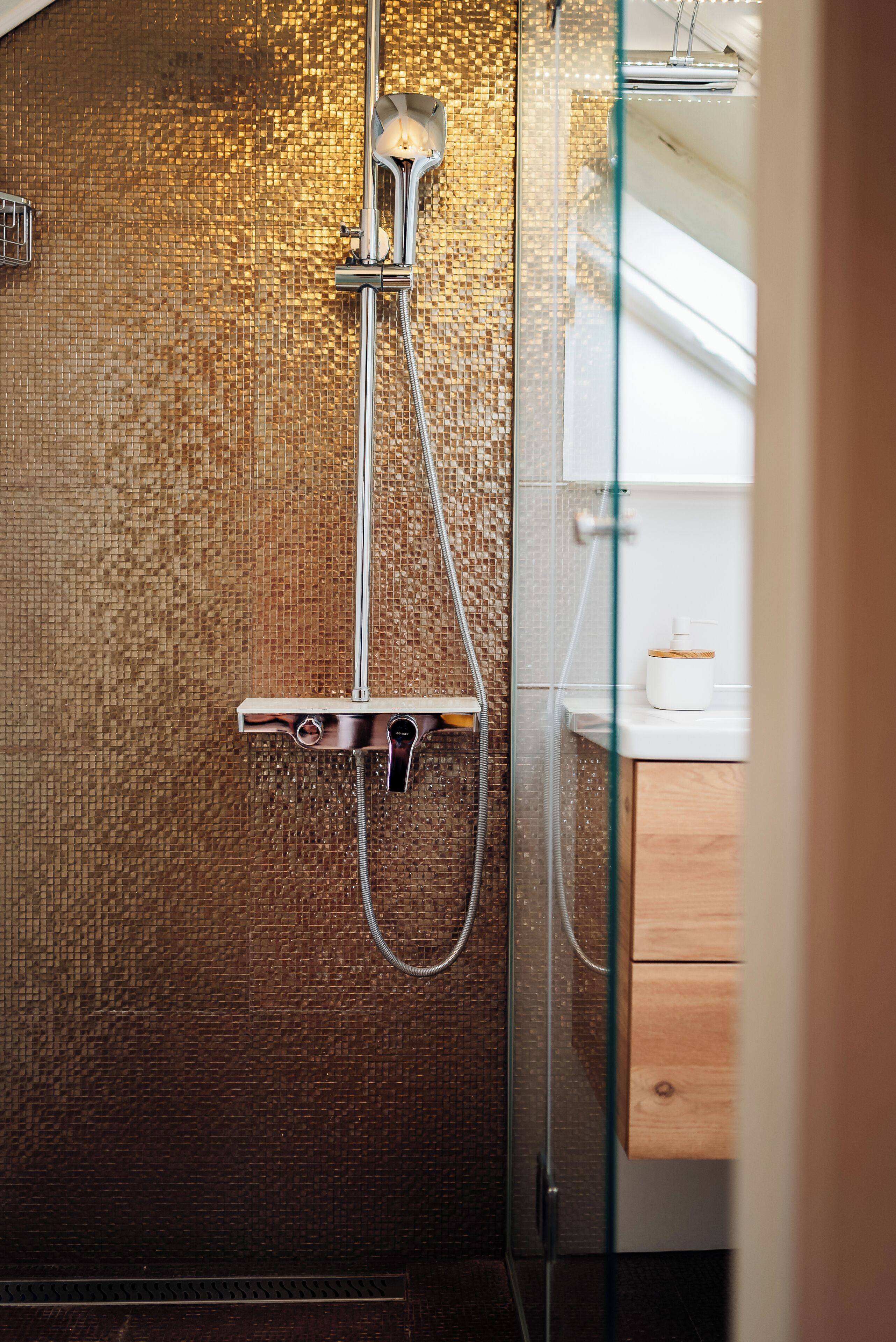 Ein modernes Badezimmer mit einer Glaskabinentrennung für die Dusche, einer gefliesten Wand und einem Holzschrank.