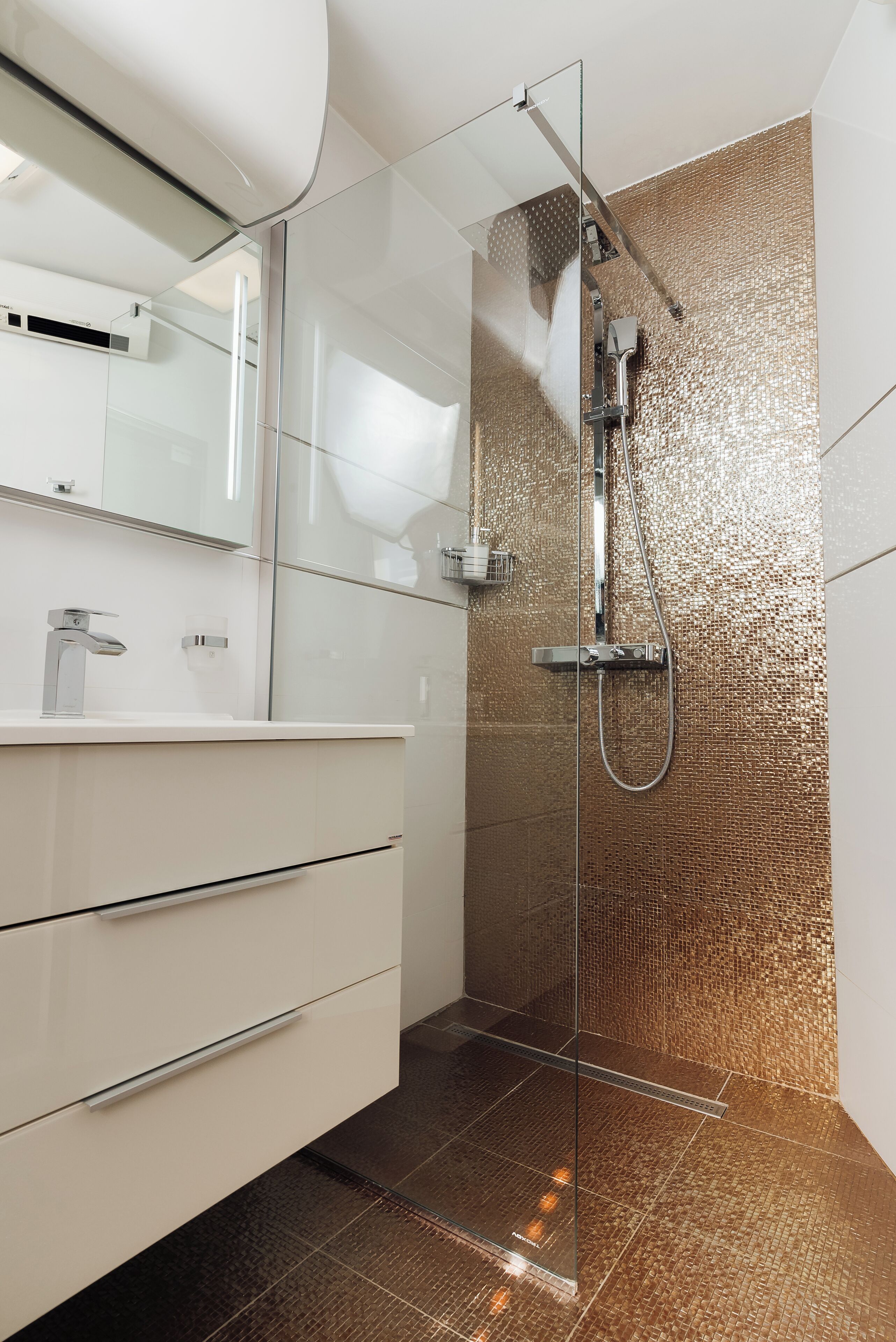A modern bathroom with a glass-enclosed shower, a white vanity with a mirror, and a textured wall.
