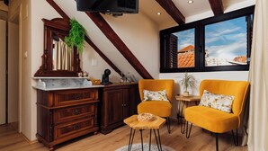A cozy living room with a wooden cabinet, two yellow chairs, a small table, and a large window with a view of buildings. - Villa Trogir Stars (Trogir)