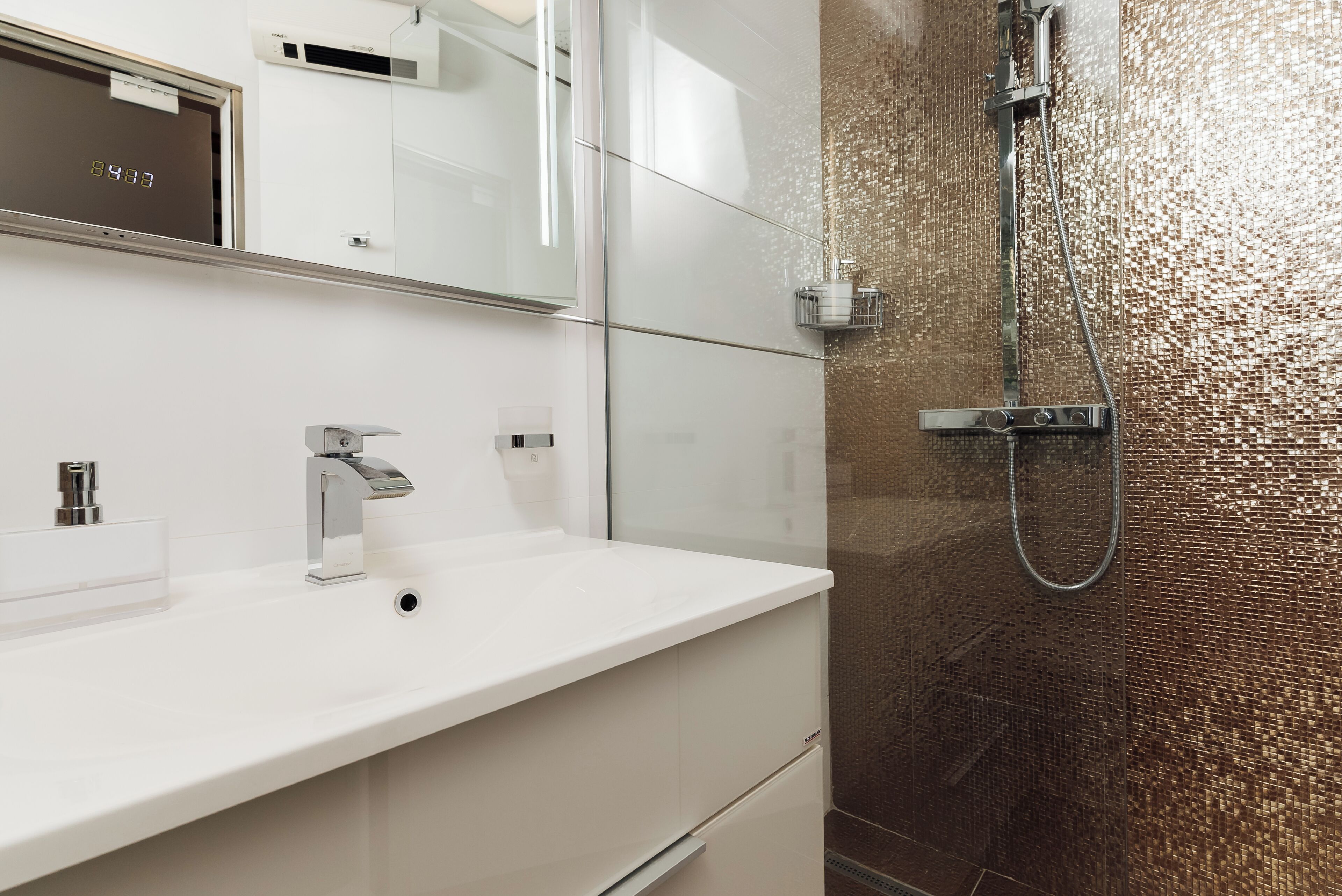 Een moderne badkamer met een wit wastafelmeubel, een grote spiegel en een douche met een gestructureerde wand.