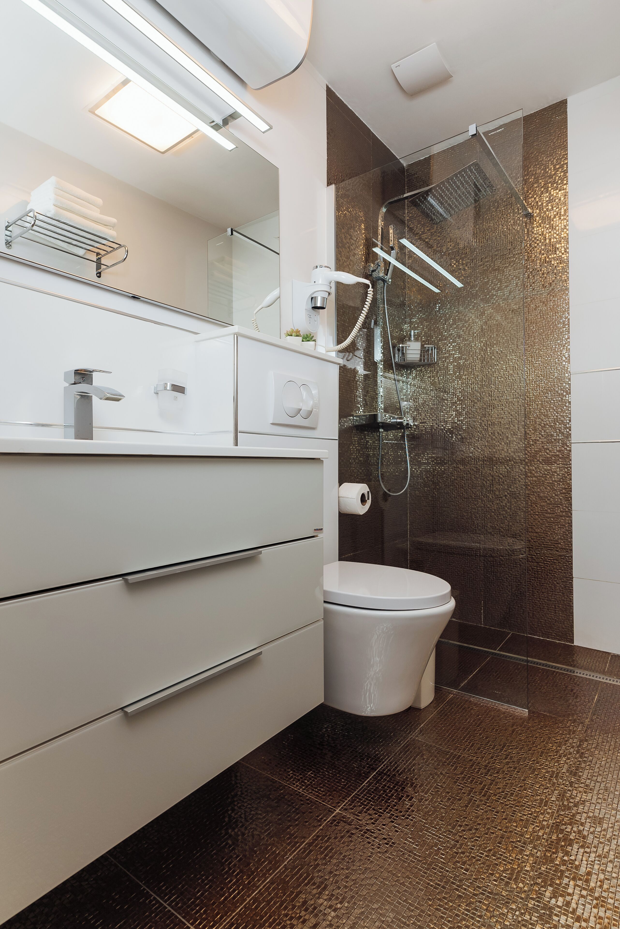 Un bagno moderno con box doccia in vetro, un WC bianco e un mobile lavabo con specchio e portasciugamani.