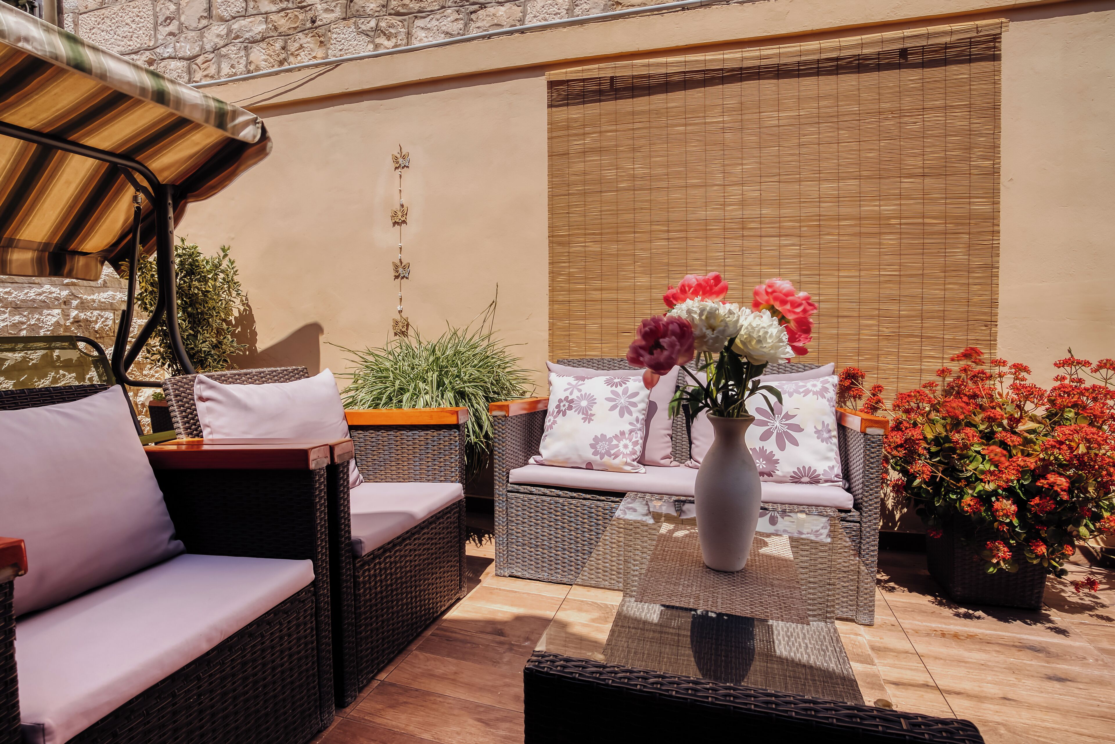 A patio area with wicker furniture, a table, and potted plants.