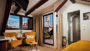 A room with a bed, two chairs, a small table, a potted plant, and a view of a building through a window. - Villa Trogir Stars (Trogir)